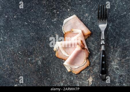 Jambon fumé en tranches. Viande de porc savoureuse et fourchette sur la table de cuisine ancienne. Vue de dessus. Banque D'Images
