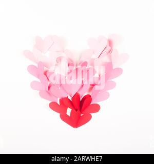 Coeur fait de petits coeurs de papier de couleur rouge et rose sur un fond blanc. Disposition minimaliste de la Saint-Valentin. Vue sur le dessus, plat. Banque D'Images