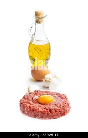 Steak de tartare de boeuf, jaune, ail et huile isolés sur fond blanc. Banque D'Images