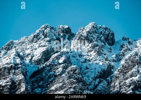 Gros plan sur les sommets enneigés des montagnes escarpés en clair ciel bleu Banque D'Images