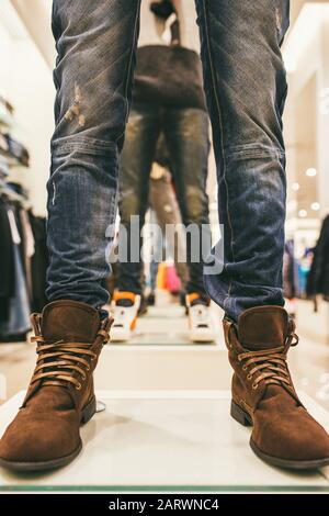 jambes de mannequins dans le magasin vêtues de jeans bleus et chaussures en cuir marron Banque D'Images