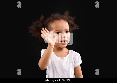 Portrait de la petite fille afro-américaine sur fond sombre Banque D'Images