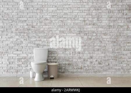 Cuvette de toilettes près du mur de briques légères Banque D'Images