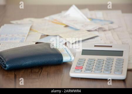 Pile de factures, portefeuille et calculatrice sur table en bois Banque D'Images