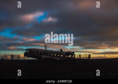 Abandonné DC plane sur Solheimasandur entouré par des personnes sous un ciel nuageux au coucher du soleil Banque D'Images