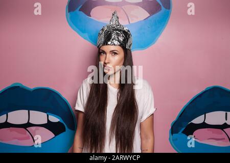 Jolie jeune femme portant un chapeau de toinfoil pour la protection. Concept de théorie du complot. Banque D'Images