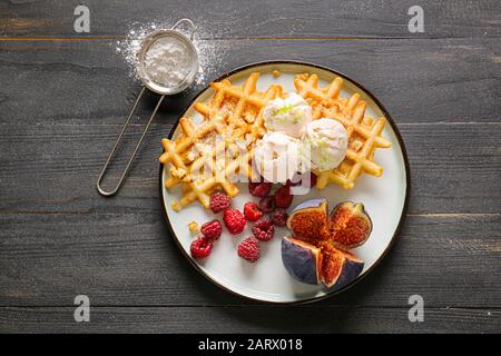 Assiette avec gaufres savoureuses, baies et figue sur table Banque D'Images