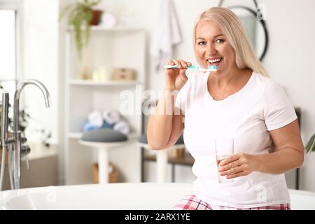 Femme mûre se brossant les dents à la maison Banque D'Images