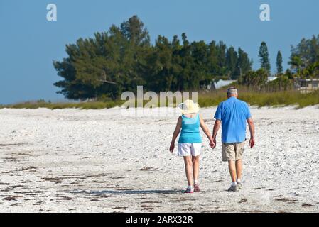 Holmes BEACH, ANNA MARIA ISLAND, FL / USA - 1 mai 2018: Couple senior tenant les mains tout en prenant une promenade tôt le matin sur la plage. Banque D'Images