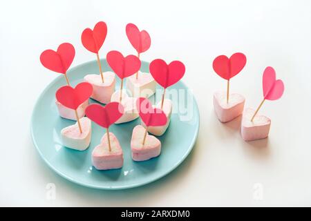 Marshmallows et coeurs de papier sur des brochettes coincées dans les meringues Banque D'Images