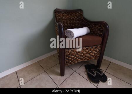 Fauteuil En Rotin Avec Serviette Propre Et Chaussons De Douche Banque D'Images