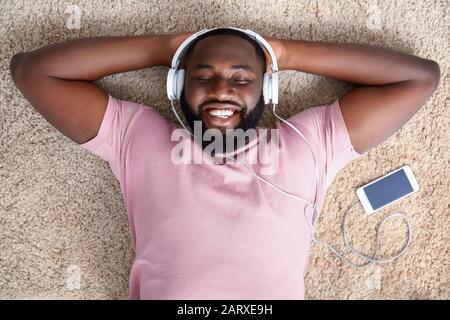 Homme afro-américain écoutant de la musique à la maison, vue de dessus Banque D'Images