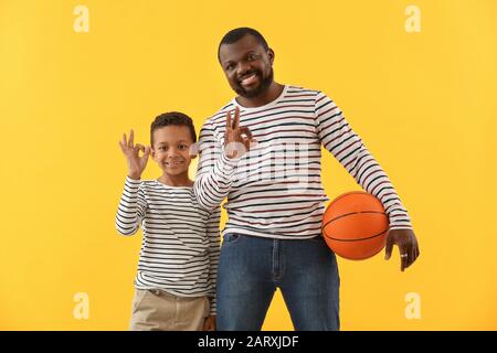 Portrait de l'homme afro-américain et de son petit fils avec balle montrant OK sur fond de couleur Banque D'Images