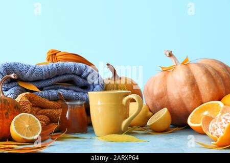 Belle composition d'automne avec tasse de thé, agrumes, confiture savoureuse et sweaters sur fond de couleur Banque D'Images