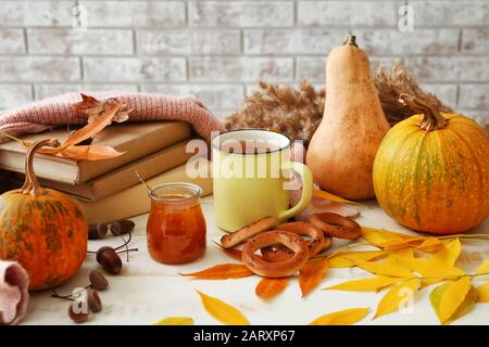 Belle composition d'automne avec tasse de thé, confiture savoureuse et crépitements sur table blanche Banque D'Images