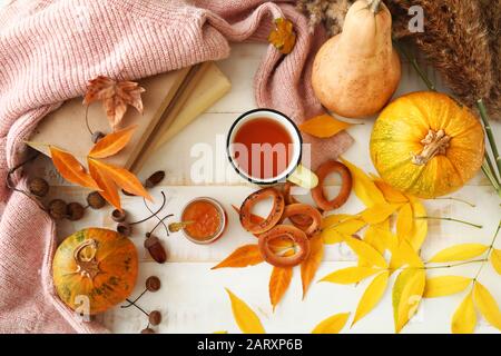 Belle composition d'automne avec tasse de thé, confiture savoureuse et crépitements sur table blanche Banque D'Images