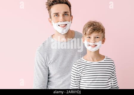 Père et son petit fils avec de la mousse à raser sur leurs visages sur fond de couleur Banque D'Images