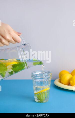 Woman pouring limonade fraîche dans un verre sur la table Banque D'Images