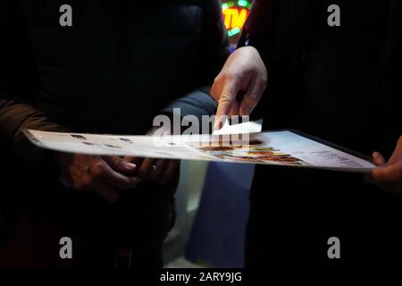 New York, NY / USA - 29 décembre 2019: Deux femmes pointent vers un menu, décidant ce qu'il faut manger pour dîner comme ils attendent à l'extérieur Banque D'Images