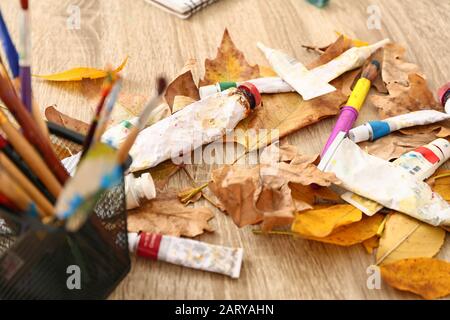 Tubes avec peintures et feuilles d'automne sur table Banque D'Images