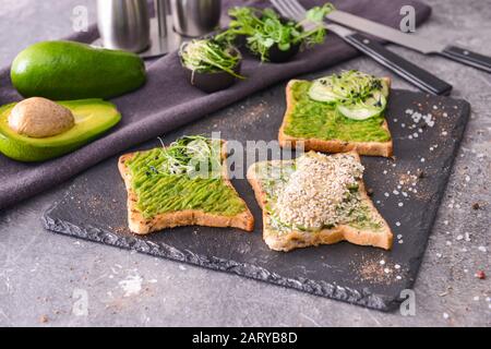 Plaque d'ardoise avec de délicieux sandwichs avocat sur fond gris Banque D'Images