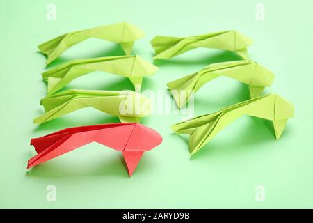 Les poissons origami rouges parmi les poissons verts sur fond de couleur. Concept d'unicité Banque D'Images