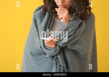 Femme malade mesurant la température sur fond de couleur Banque D'Images
