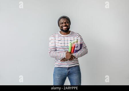 Homme afro-américain avec des livres sur fond clair Banque D'Images