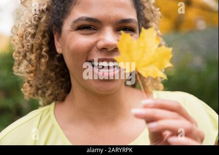 Smiling woman holding autumn leaf Banque D'Images