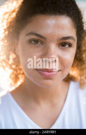 Femme aux cheveux bouclés regardant l'appareil photo Banque D'Images