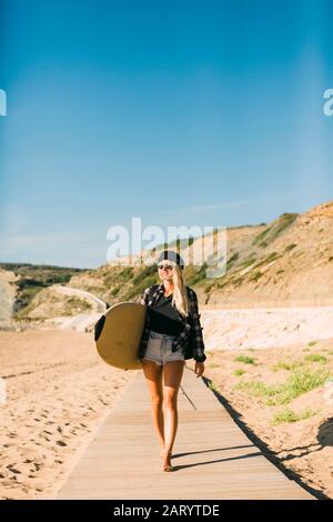 Femme tenant une planche de surf sur la promenade Banque D'Images