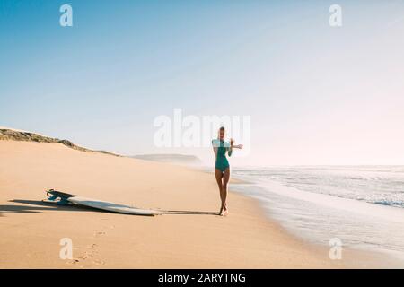 Femme portant une combinaison qui s'étend sur la plage Banque D'Images
