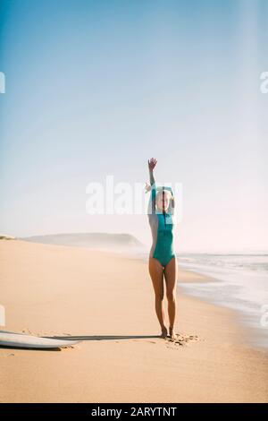 Femme portant une combinaison qui s'étend sur la plage Banque D'Images