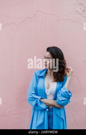 Femme souriante vêtue de bleu par un mur rose Banque D'Images