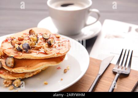 Assiette avec de délicieuses crêpes sucrées sur la table, à proximité Banque D'Images