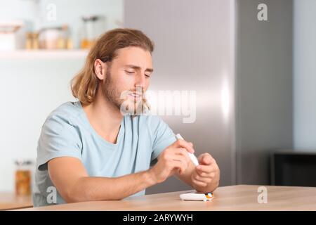 Homme diabétique prenant un échantillon de sang avec un stylo lancet Banque D'Images