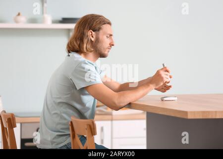 Homme diabétique prenant un échantillon de sang avec un stylo lancet Banque D'Images