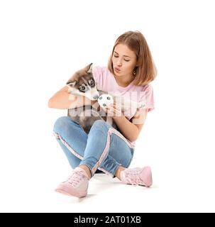 Jolie fille adolescente jouant avec le chiot Husky drôle sur fond blanc Banque D'Images