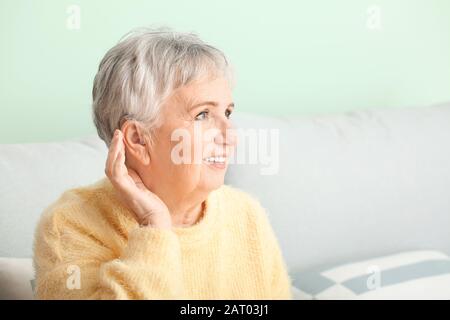 Femme senior avec aide auditive à la maison Banque D'Images