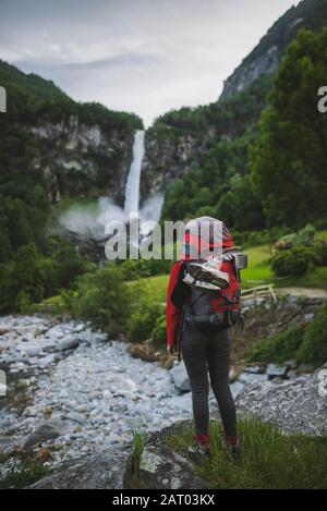 Femme portant un sac à dos avec chute d'eau à distance Banque D'Images