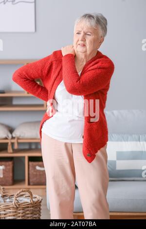 Femme senior souffrant de douleur dans l'épaule à la maison Banque D'Images