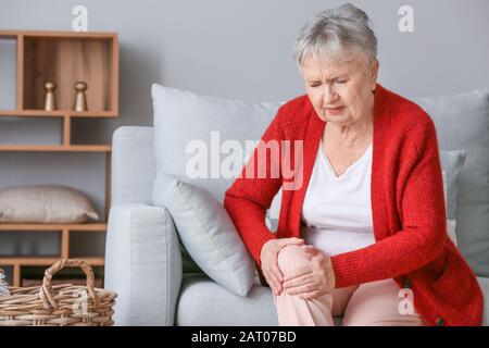 Femme senior souffrant de douleur au genou à la maison Banque D'Images