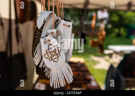 Produits en cuir fabriqués à la main en vente dans une boutique d'artisanat sur le marché de l'agriculteur local. Gros plan de petits sacs ou bourses blancs avec franges et décorations ethniques. Banque D'Images