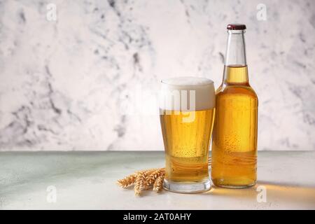 Bouteille et verre de bière savoureuse sur fond clair Banque D'Images