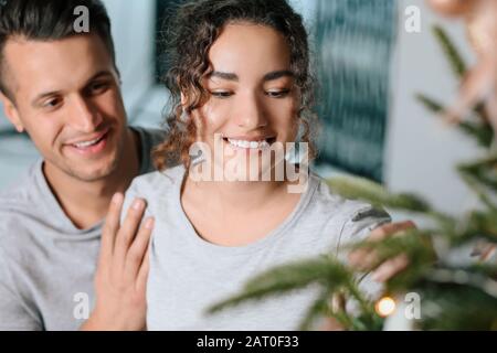 Happy young couple decorating Christmas Tree at home Banque D'Images