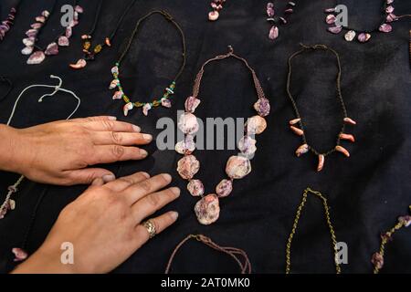 Gros plan sur les mains de l'homme reposant sur le tissu en velours noir d'un magasin de bijoux du marché fermier. Colliers faits de pierres et de pierres tout autour. Banque D'Images