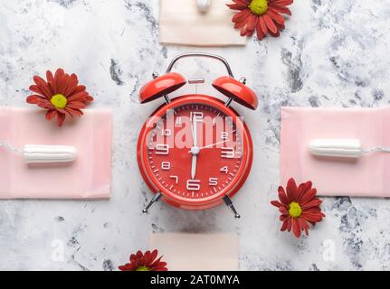Tampons menstruels avec tampons et réveil sur fond blanc. Concept menstruel Banque D'Images