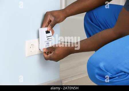 Électricien afro-américain utilisant un régulateur de tension de prise dans la chambre Banque D'Images