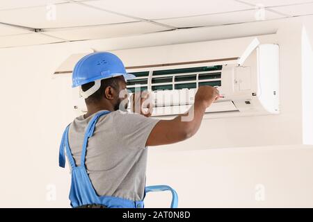 Électricien afro-américain qui répare la climatisation à l'intérieur Banque D'Images