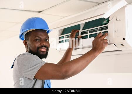 Électricien afro-américain qui répare la climatisation à l'intérieur Banque D'Images